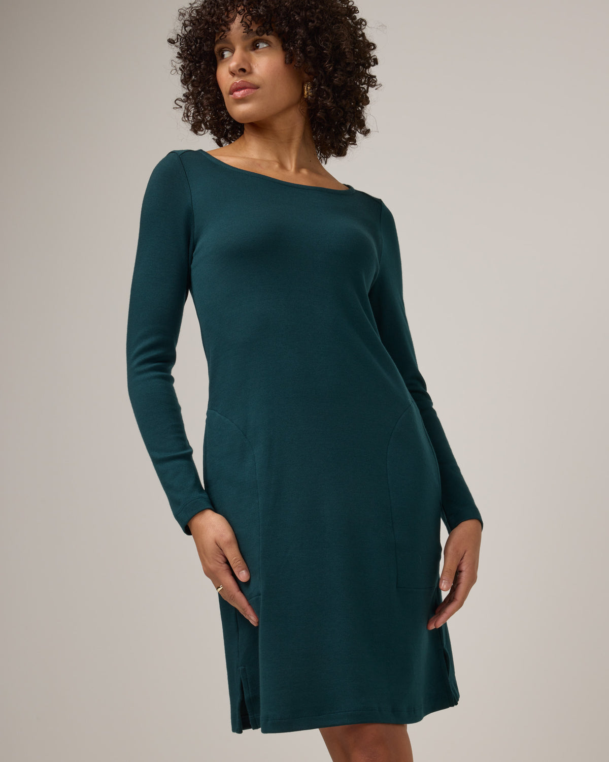 Model wearing Margo Shift Dress in Pine, a saturated forest green color. Margo Shift Dress is a merino wool long sleeve, boatneck, knee length shift dress with pockets available in sizes XS-3X Regular, S-3X Long.