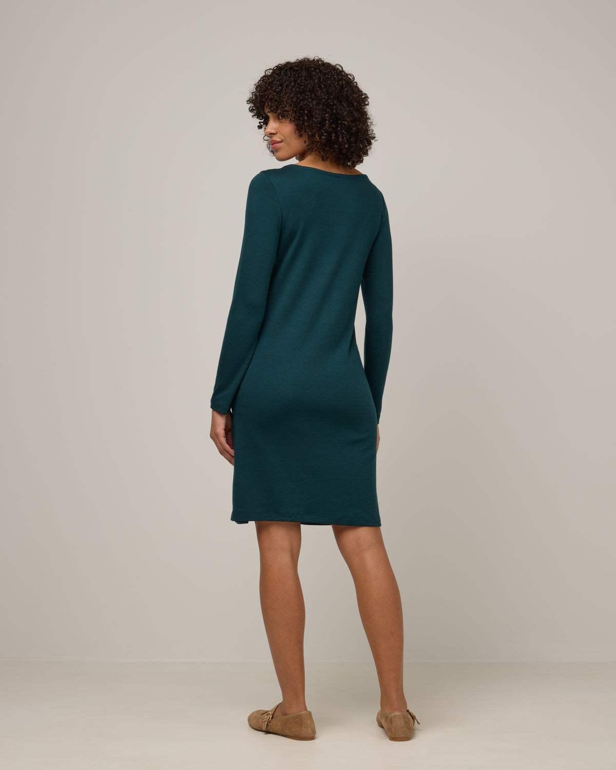 Model wearing Margo Shift Dress in Pine, a saturated forest green color. Margo Shift Dress is a merino wool long sleeve, boatneck, knee length shift dress with pockets available in sizes XS-3X Regular, S-3X Long.