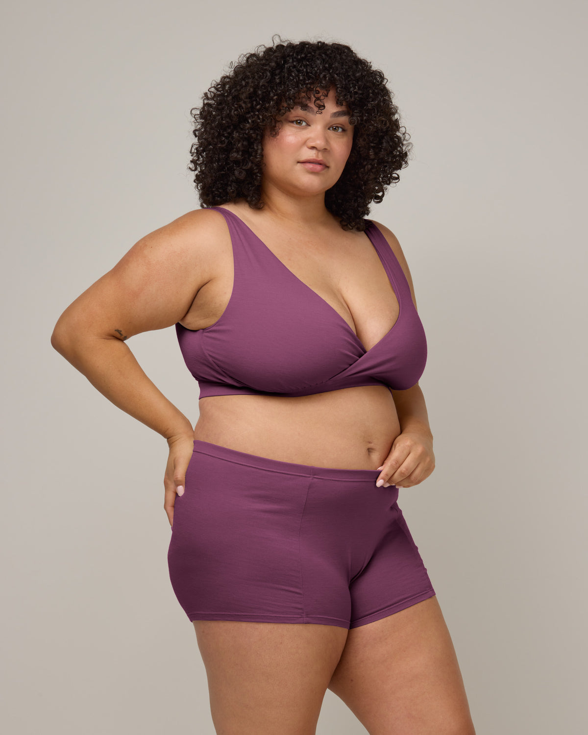 Model wearing Roam Wrap Bra in Plum, a berry pink-purple color. Roam Wrap Bra is a merino wool underwear available in sizes 1X-3X.