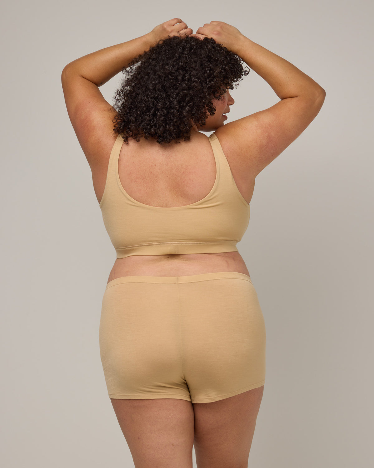 Model wearing Roam Wrap Bra in Fawn, a light nude color. Roam Wrap Bra is a merino wool underwear available in sizes 1X-3X.