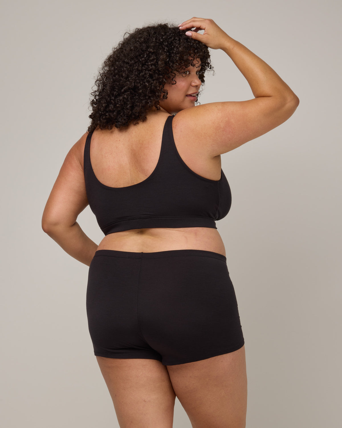 Model wearing Roam Wrap Bra in Black. Roam Wrap Bra is a merino wool underwear available in sizes 1X-3X.