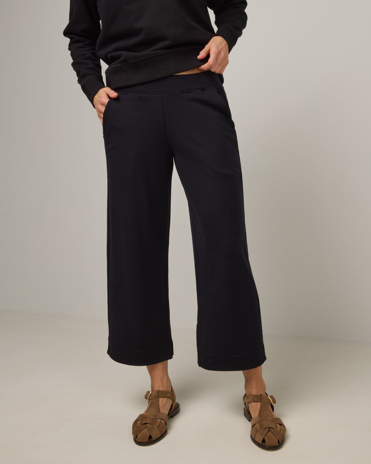 Model wearing Aspen Wide Leg Crop Sweatpants in Black. Aspen Wide Leg Crop Sweatpants is a merino wool sweatpant with pockets available in sizes XS-3X.