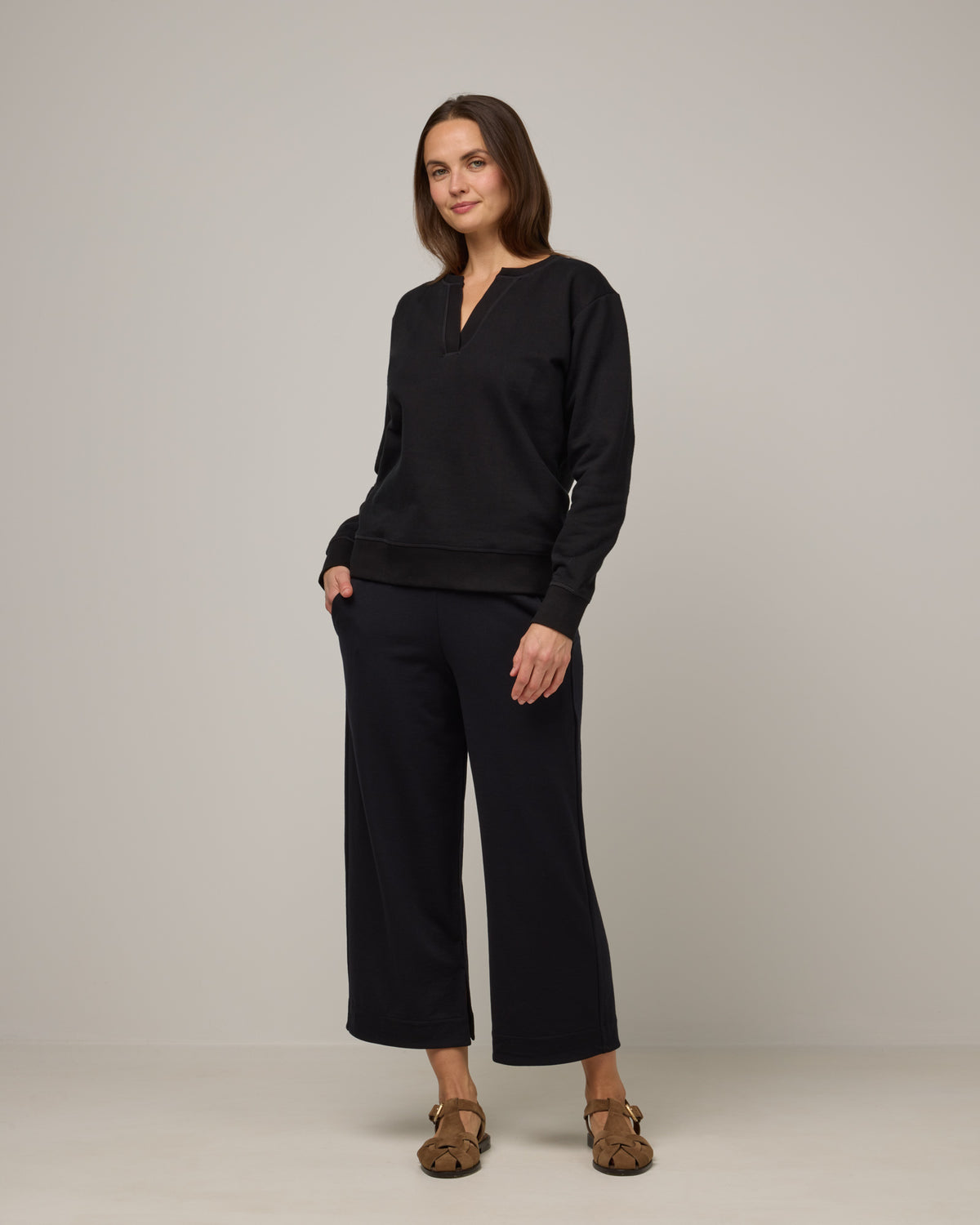 Model wearing Aspen Wide Leg Crop Sweatpants in Black. Aspen Wide Leg Crop Sweatpants is a merino wool sweatpant with pockets available in sizes XS-3X.