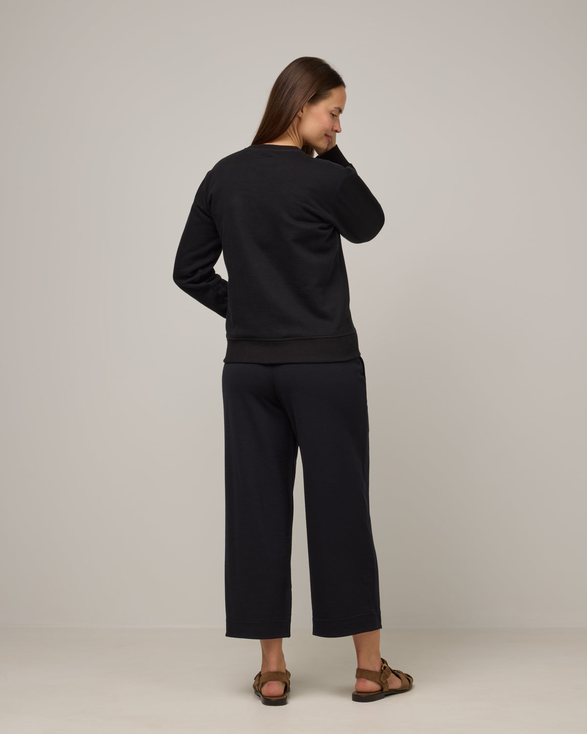 Model wearing Aspen Wide Leg Crop Sweatpants in Black. Aspen Wide Leg Crop Sweatpants is a merino wool sweatpant with pockets available in sizes XS-3X.
