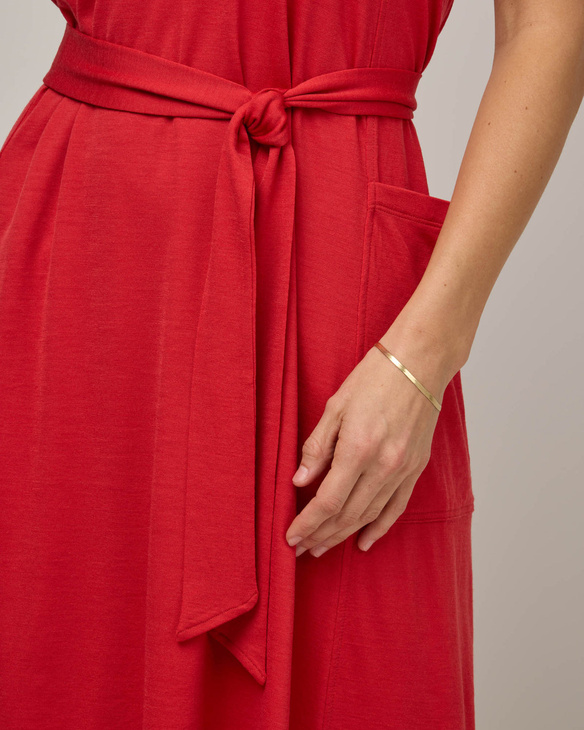 Model wearing Summer Reversible Dress in Fruit Punch, a vivid red-orange color. Summer Reversible Dress is a merino wool sleeveless, reversible, midi swing dress with pockets available in sizes XS-3X.