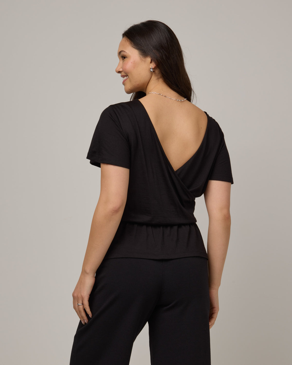 Model wearing Jeanne Flutter Sleeve Top in Black. Jeanne Flutter Sleeve Top is a merino wool short sleeve, reversible, regular fit top available in sizes XS-XXL.
