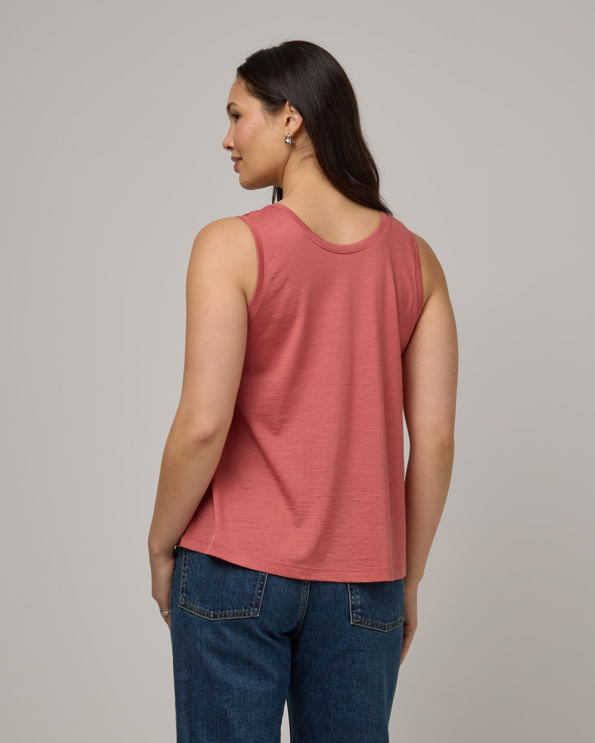 Model wearing Poppy Signature Reversible Tank in Dusty Cedar, a soft pink-coral color. Poppy Signature Reversible Tank is a merino wool sleeveless, reversible, relaxed fit top available in sizes XS-3X.