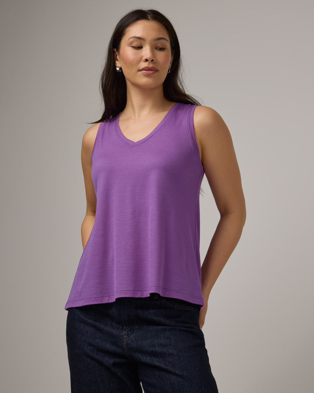 Model wearing Poppy Signature Reversible Tank in Purple Pansy, a bright, saturated purple color. Poppy Signature Reversible Tank is a merino wool sleeveless, reversible, relaxed fit top available in sizes XS-3X.