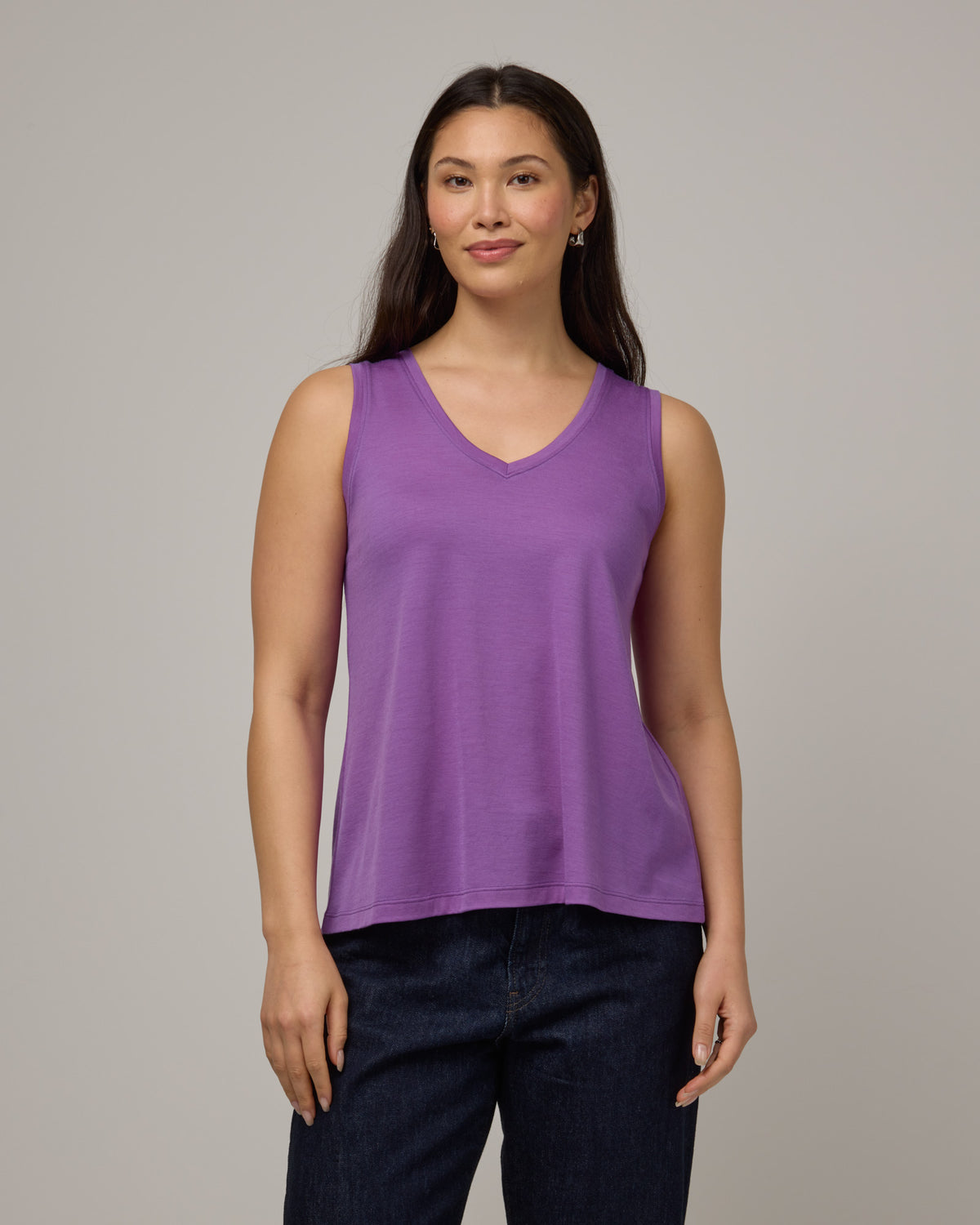 Model wearing Poppy Signature Reversible Tank in Purple Pansy, a bright, saturated purple color. Poppy Signature Reversible Tank is a merino wool sleeveless, reversible, relaxed fit top available in sizes XS-3X.
