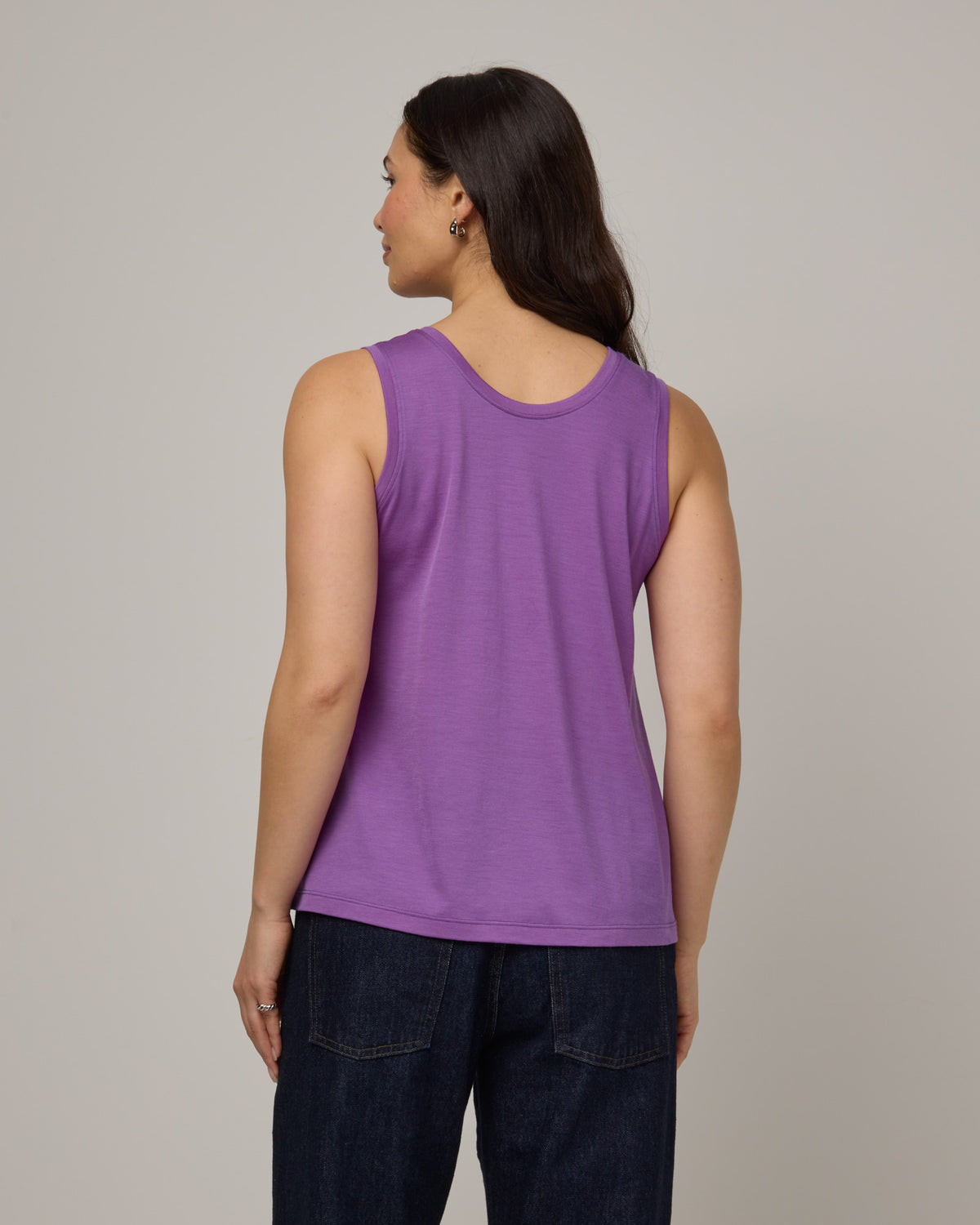 Model wearing Poppy Signature Reversible Tank in Purple Pansy, a bright, saturated purple color. Poppy Signature Reversible Tank is a merino wool sleeveless, reversible, relaxed fit top available in sizes XS-3X.