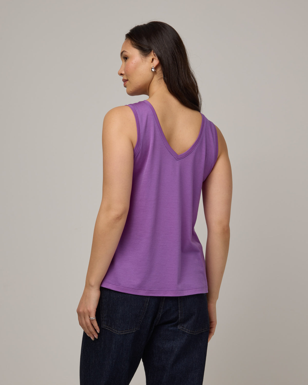 Model wearing Poppy Signature Reversible Tank in Purple Pansy, a bright, saturated purple color. Poppy Signature Reversible Tank is a merino wool sleeveless, reversible, relaxed fit top available in sizes XS-3X.