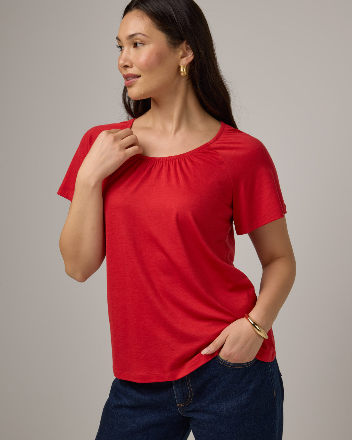 Model wearing Lilah Signature Gathered Neck Tee in Fruit Punch, a vivid red-orange color. Lilah Signature Gathered Neck Tee is a merino wool short sleeve, scoop neck, relaxed fit tee available in sizes XS-3X.