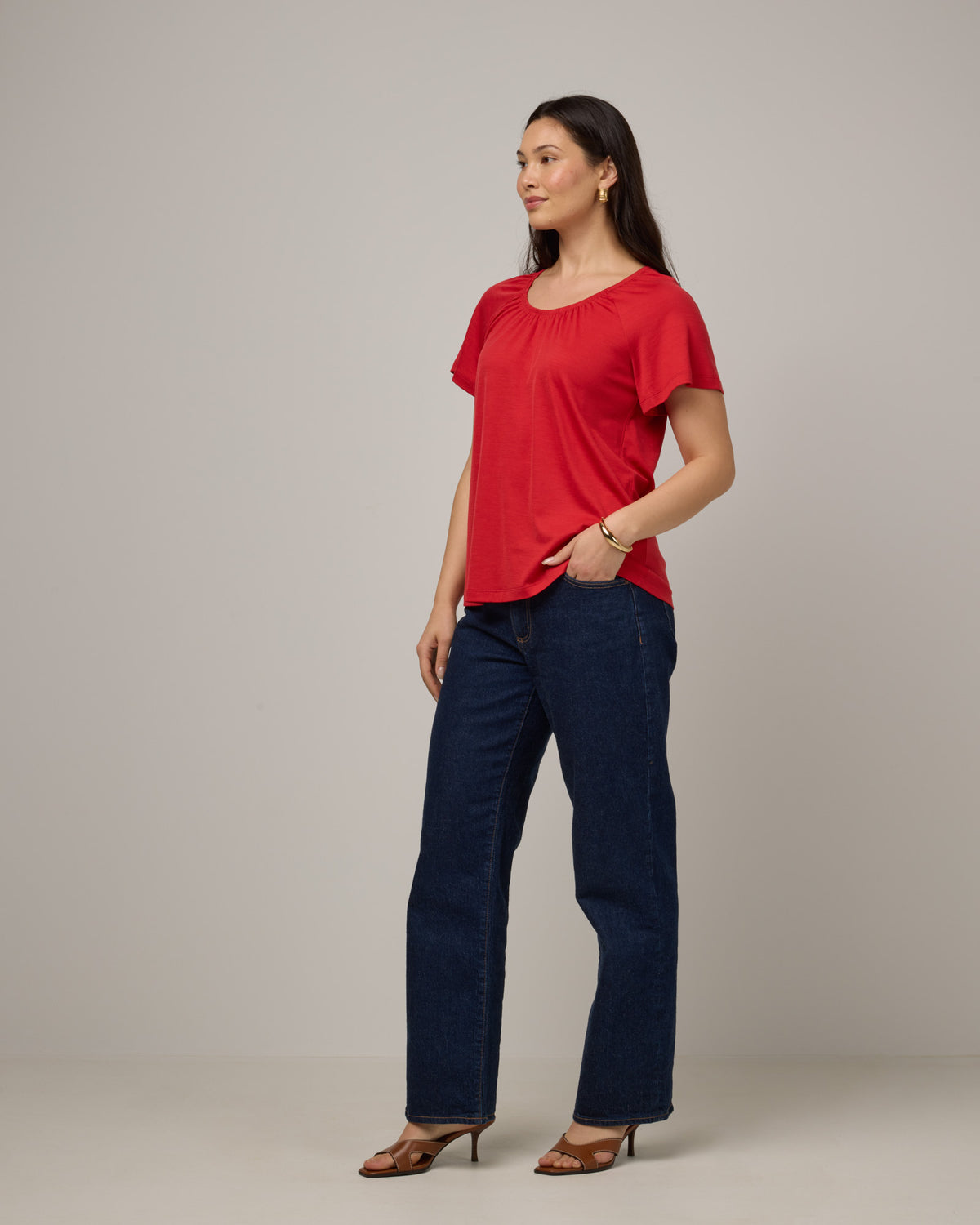 Model wearing Lilah Signature Gathered Neck Tee in Fruit Punch, a vivid red-orange color. Lilah Signature Gathered Neck Tee is a merino wool short sleeve, scoop neck, relaxed fit tee available in sizes XS-3X.