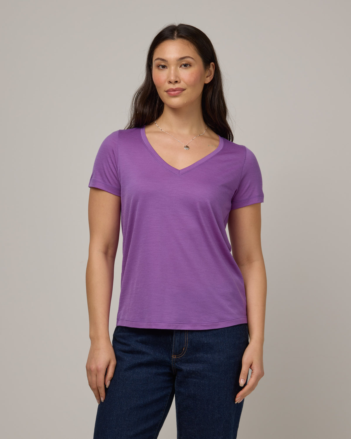 Model wearing Morgan V-Neck Tee in Purple Pansy, a bright, saturated purple color. Morgan V-Neck Tee is a merino wool short sleeve, v-neck, regular fit tee available in sizes XS-3X.