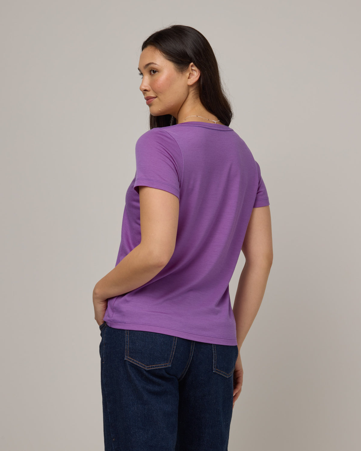 Model wearing Morgan V-Neck Tee in Purple Pansy, a bright, saturated purple color. Morgan V-Neck Tee is a merino wool short sleeve, v-neck, regular fit tee available in sizes XS-3X.