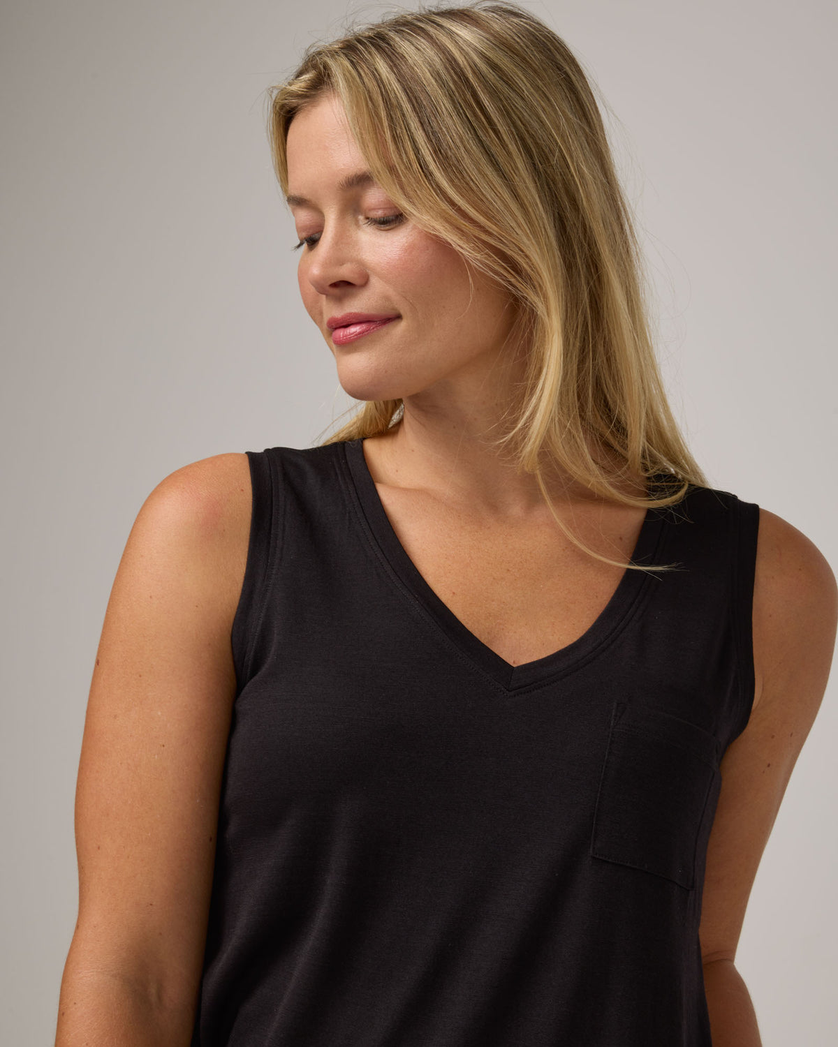 Model wearing Penelope Pocket Tank in Black. Penelope Pocket Tank is a merino wool sleeveless, v-neck tank with a pocket available in sizes XS-3X.