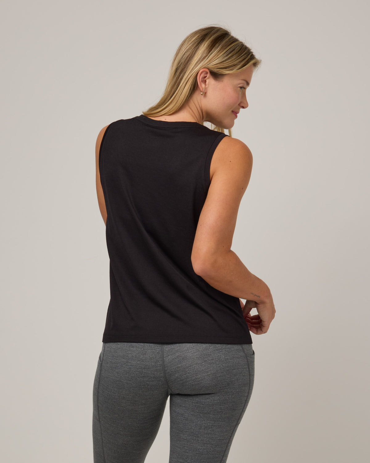 Model wearing Penelope Pocket Tank in Black. Penelope Pocket Tank is a merino wool sleeveless, v-neck tank with a pocket available in sizes XS-3X.