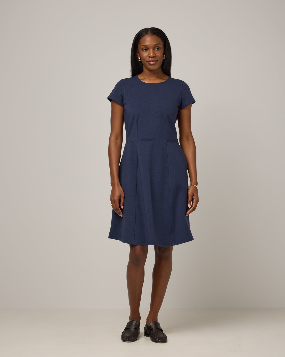 Model wearing Anais Fit & Flare Dress in Washed Navy. Anais Fit & Flare Dress is a merino wool short sleeve, square neck, knee length fit & flare dress with pockets available in sizes XS-XXL.