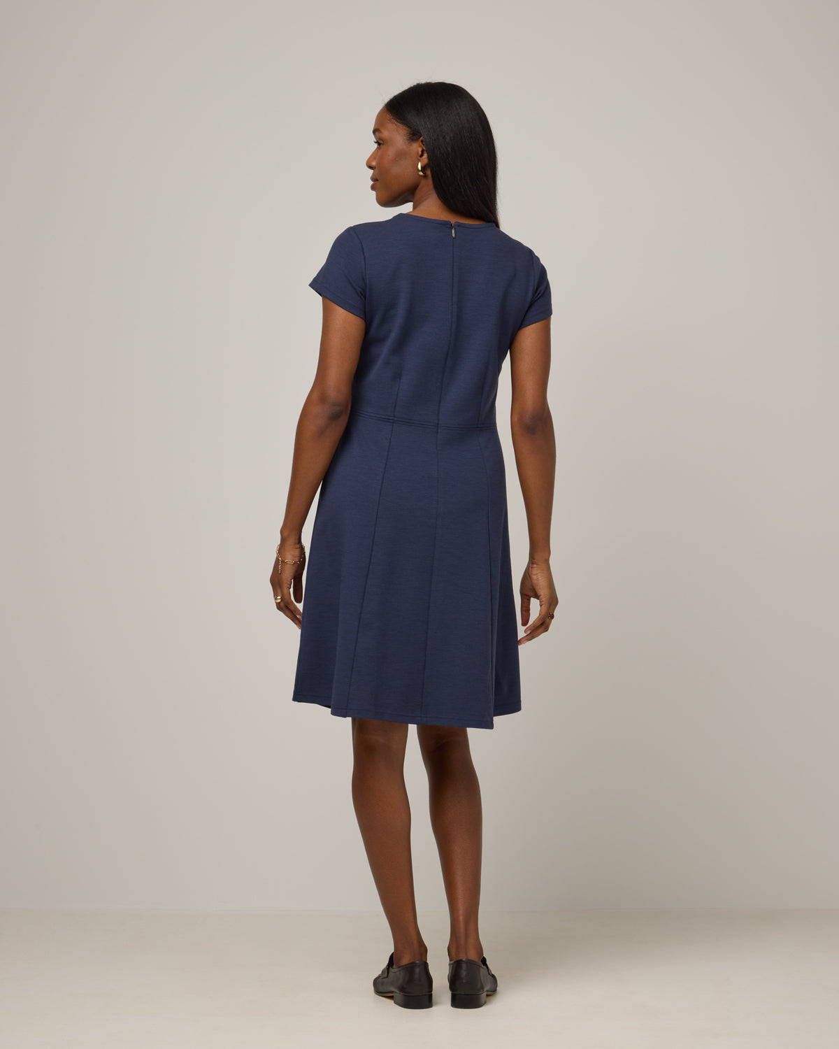 Model wearing Anais Fit & Flare Dress in Washed Navy. Anais Fit & Flare Dress is a merino wool short sleeve, square neck, knee length fit & flare dress with pockets available in sizes XS-XXL.