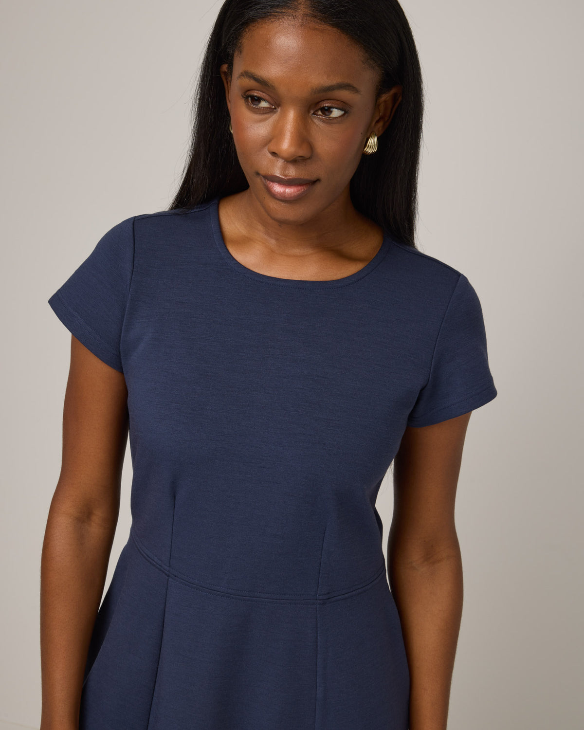 Model wearing Anais Fit & Flare Dress in Washed Navy. Anais Fit & Flare Dress is a merino wool short sleeve, square neck, knee length fit & flare dress with pockets available in sizes XS-XXL.
