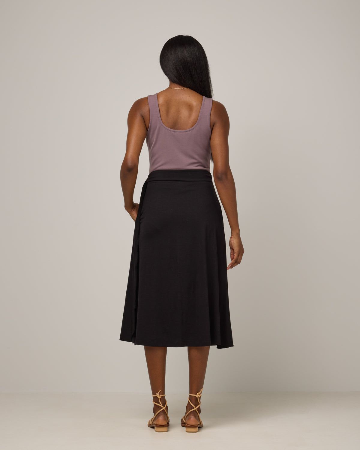 Model wearing Skye Wrap Skirt in Black. Skye Wrap Skirt is a merino wool midi length skirt with pockets available in sizes XS-3X.