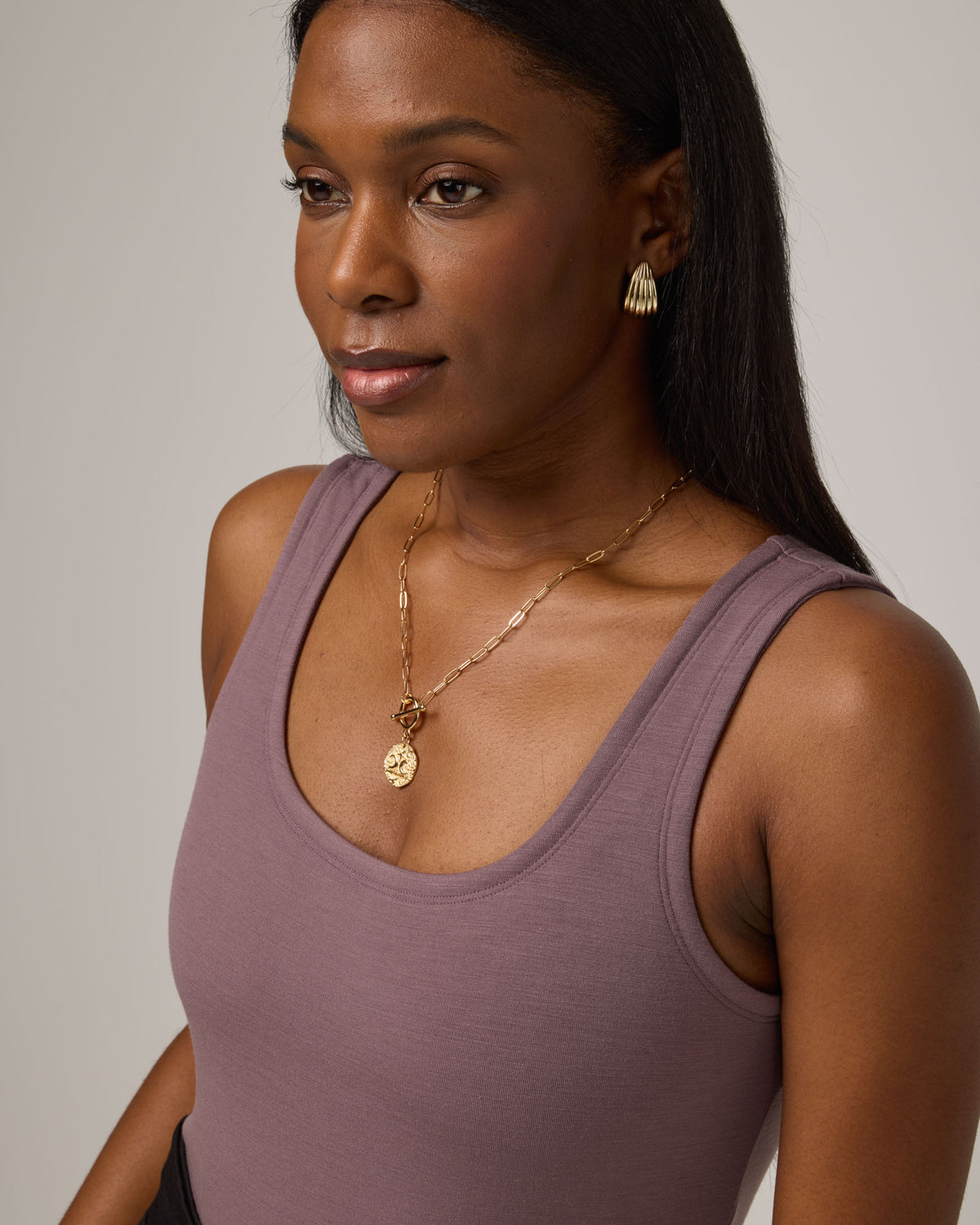 Model wearing Britt Bodysuit in Lavender, a dusky muted purple color. Britt Bodysuit is a merino wool slim fit, sleeveless, scoop neck bodysuit available in sizes XS-XXL.