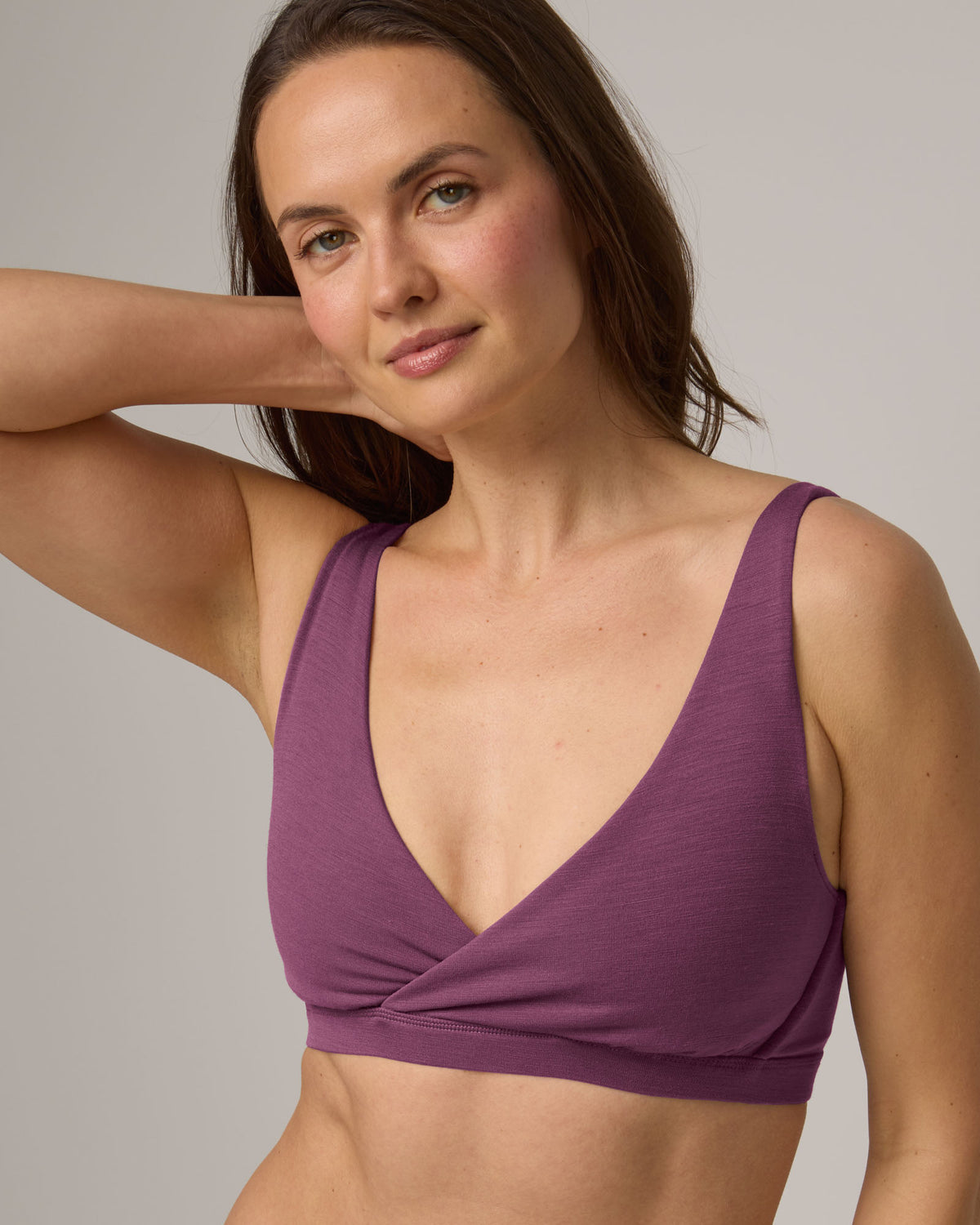 Model wearing Roam Convertible Wrap Bra in Plum, a berry pink-purple color. Roam Convertible Wrap Bra is a merino wool underwear available in sizes XS-XXL.