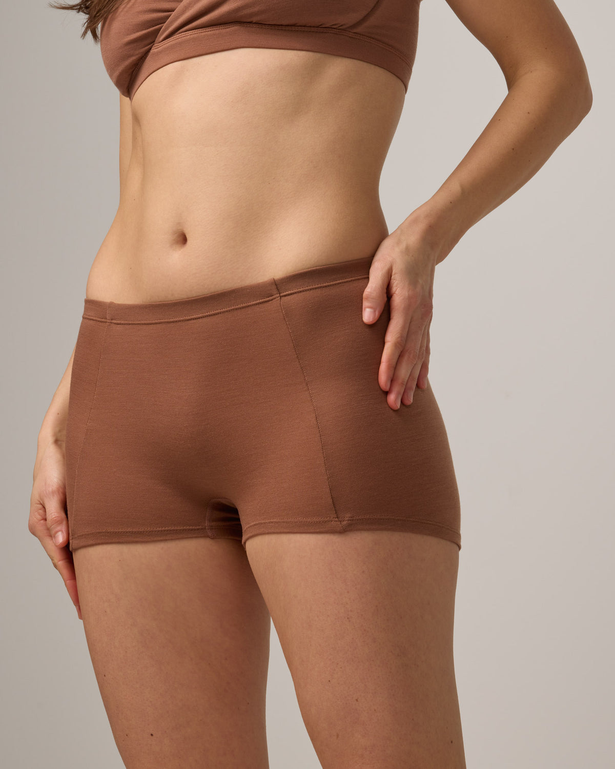 Model wearing Roam High Waist Shortie in Mocha Brown, a medium-dark nude color. Roam High Waist Shortie is a merino wool underwear available in sizes XS-3X.