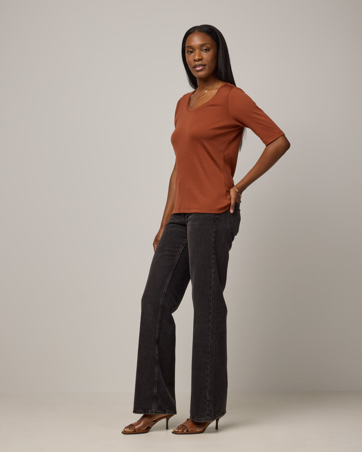 Model wearing Celine Ribbed Elbow Sleeve Tee in Cinnamon, a reddish-brown rust color. Celine Ribbed Elbow Sleeve Tee is a merino wool short sleeve, scoop neck tee available in sizes XS-3X.