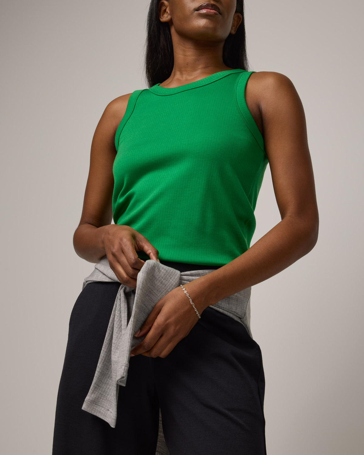 Model wearing Lily Ribbed Tee in Verde, a bright Kelly green color. Lily Ribbed Tee is a merino wool sleeveless, crew neck tank available in sizes XS-3X. 