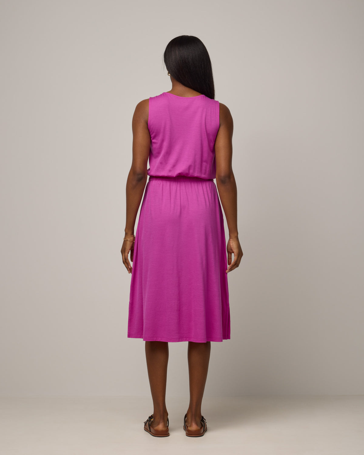 Model wearing Sofia Fit & Flare Dress in Petunia, a bright fuchsia pink-purple color. Sofia Fit & Flare Dress is a merino wool sleeveless, crew neck, midi fit & flare dress with pockets available in sizes XS-XXL.
