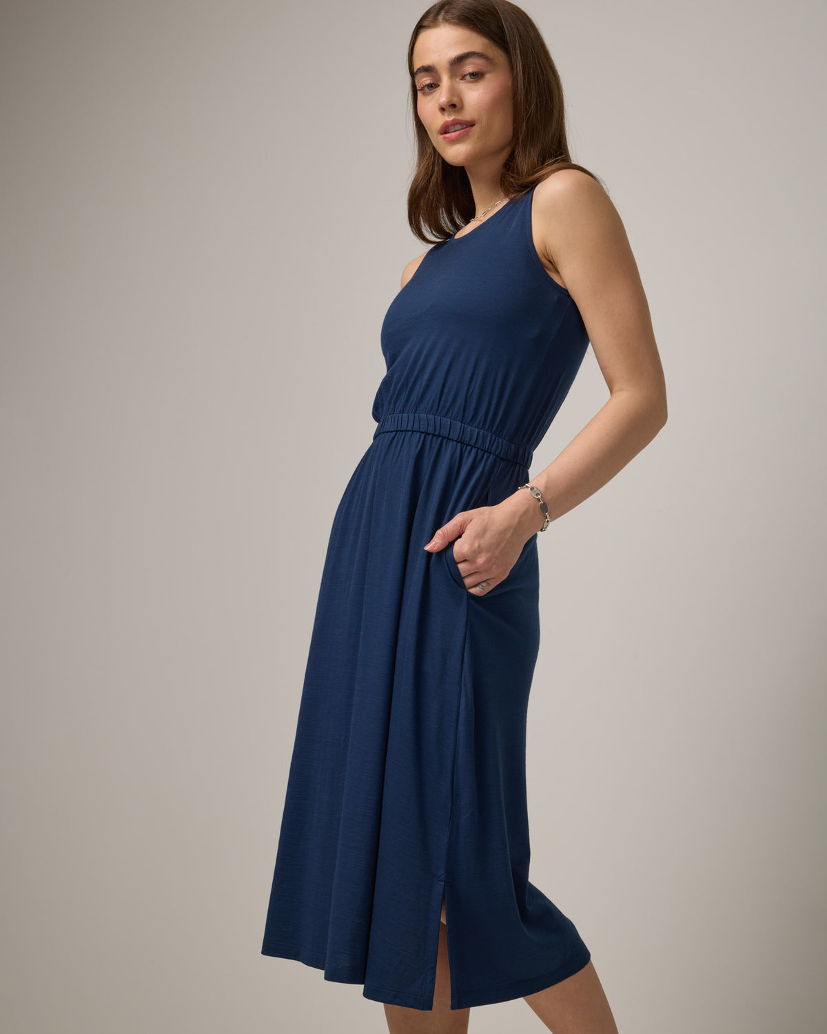 Model wearing Sofia Fit & Flare Dress in Marine Blue, a dark royal blue color. Sofia Fit & Flare Dress is a merino wool sleeveless, crew neck, midi fit & flare dress with pockets available in sizes XS-XXL.
