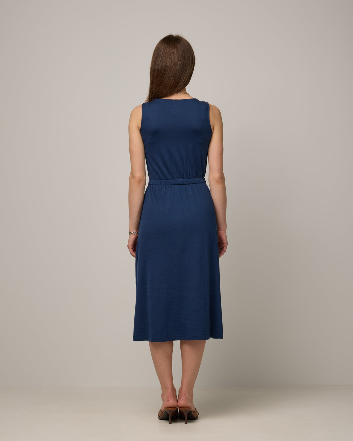 Model wearing Sofia Fit & Flare Dress in Marine Blue, a dark royal blue color. Sofia Fit & Flare Dress is a merino wool sleeveless, crew neck, midi fit & flare dress with pockets available in sizes XS-XXL.