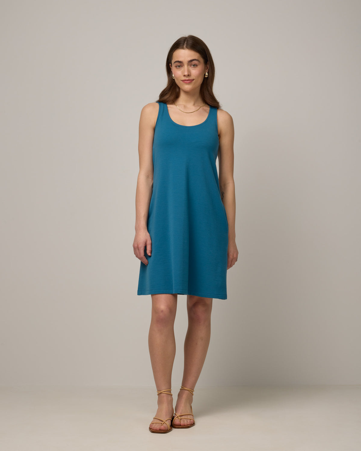 Model wearing Drew Tank Dress in Ocean Teal, a medium blue-green color. Drew Tank Dress is a merino wool sleeveless, scoop neck, knee-length swing dress available in sizes XS-3X. 