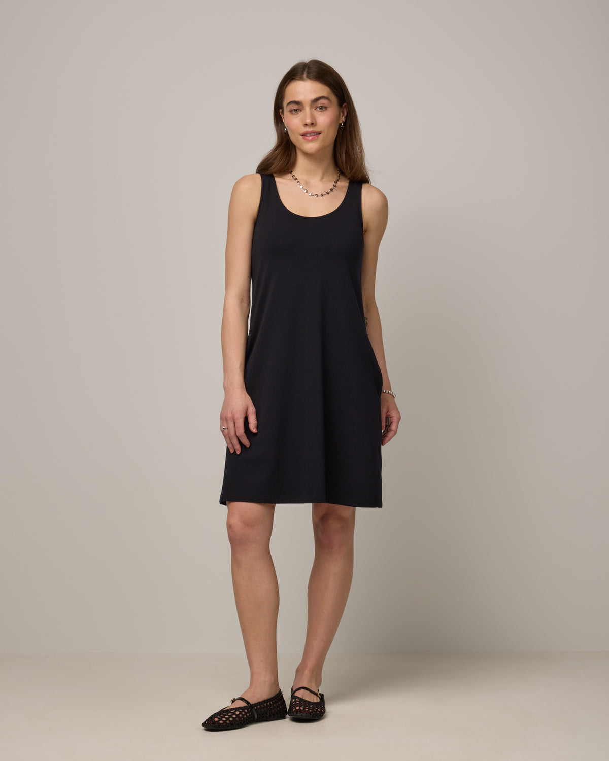 Model wearing Drew Tank Dress in Black. Drew Tank Dress is a merino wool sleeveless, scoop neck, knee length swing dress available in sizes XS-3X. 