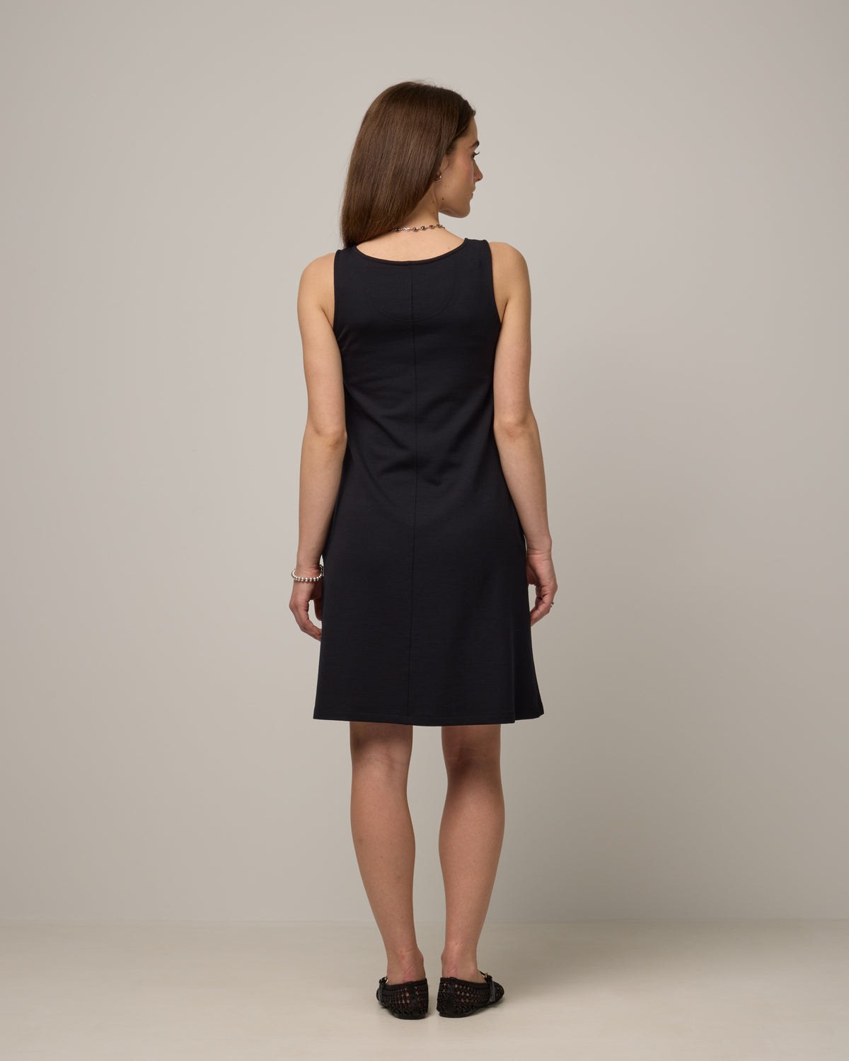 Model wearing Drew Tank Dress in Black. Drew Tank Dress is a merino wool sleeveless, scoop neck, knee length swing dress available in sizes XS-3X. 