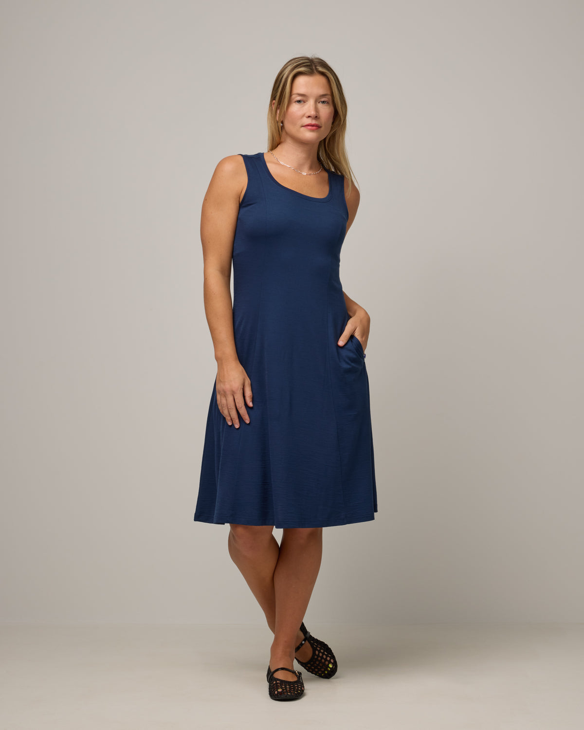 Model wearing Flora Swing Dress in Marine Blue, a deep royal blue color. Flora Swing Dress is a merino wool sleeveless, scoop neck, knee length swing dress with pockets available in sizes XS-3X.