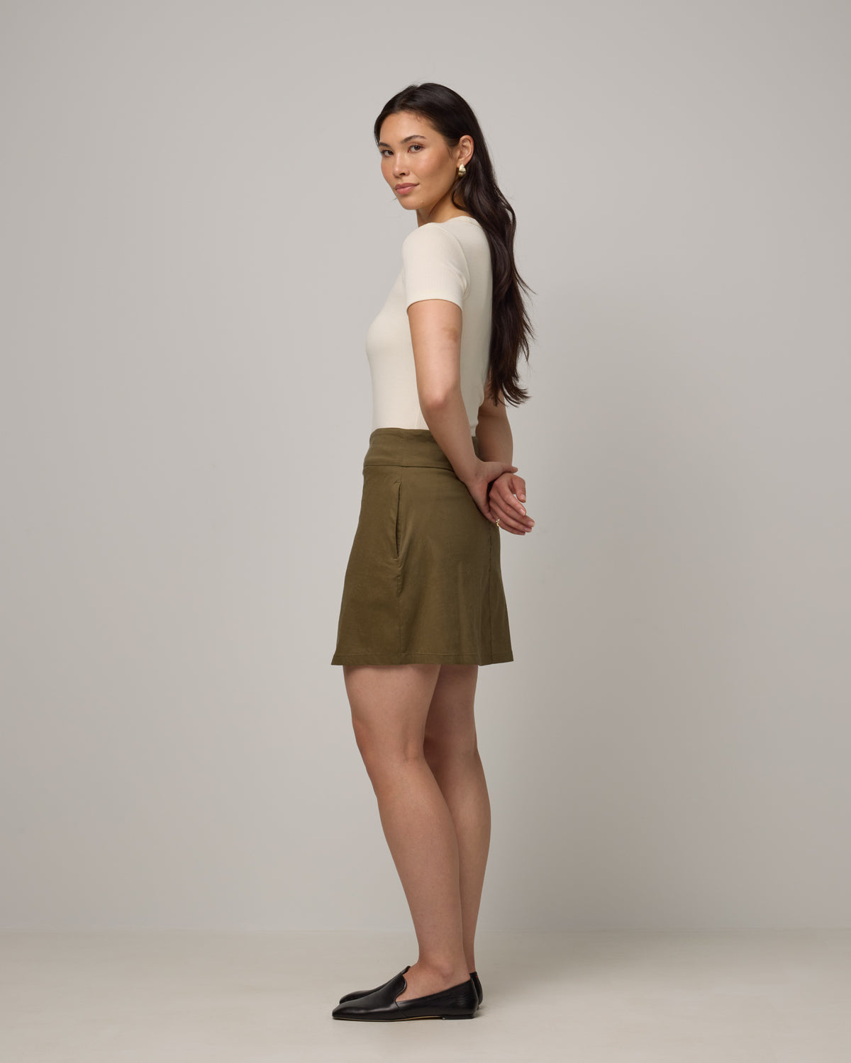 Model wearing Adventure Skort in Olive. Adventure Skort is a merino wool above-knee length skort with pockets available in sizes XS-XXL.