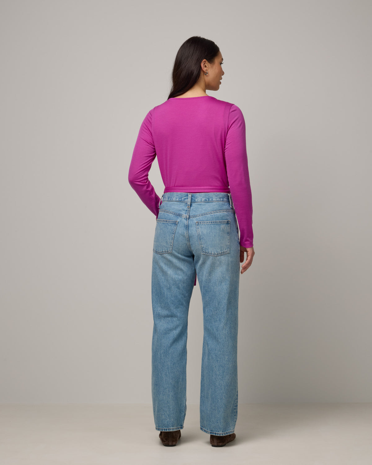 Model wearing Natalia Wrap Top in Petunia, a bright fuchsia pink-purple color. Natalia Wrap Top is a merino wool long sleeve, v-neck, slim fit top available in sizes XS-3X.