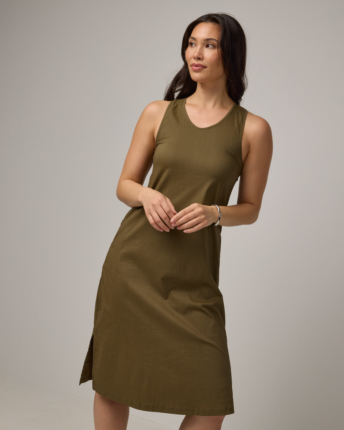 Model wearing Acadia Racerback Dress in Olive. Acadia Racerback Dress is a merino wool sleeveless, v-neck, midi length fitted dress available in sizes XS-XXL.