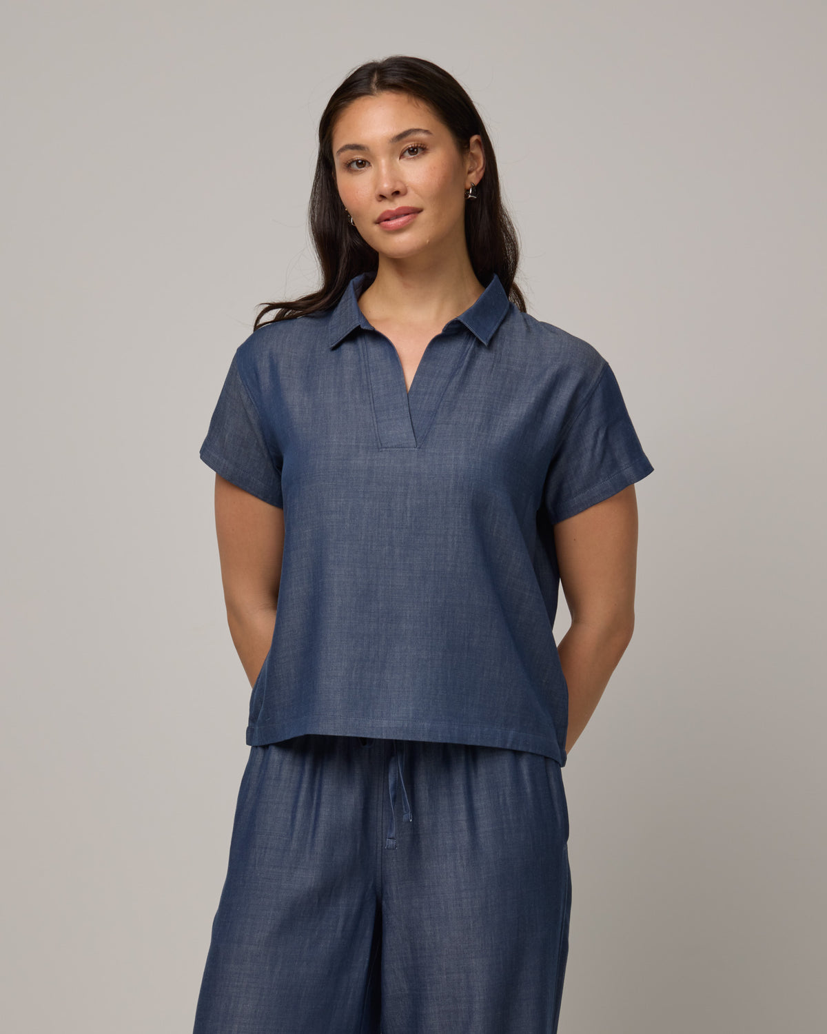 Model wearing Hollis Chambray Top in Dark Blue. Hollis Chambray Top is a merino wool short sleeve, collared top available in sizes XS-XXL. 