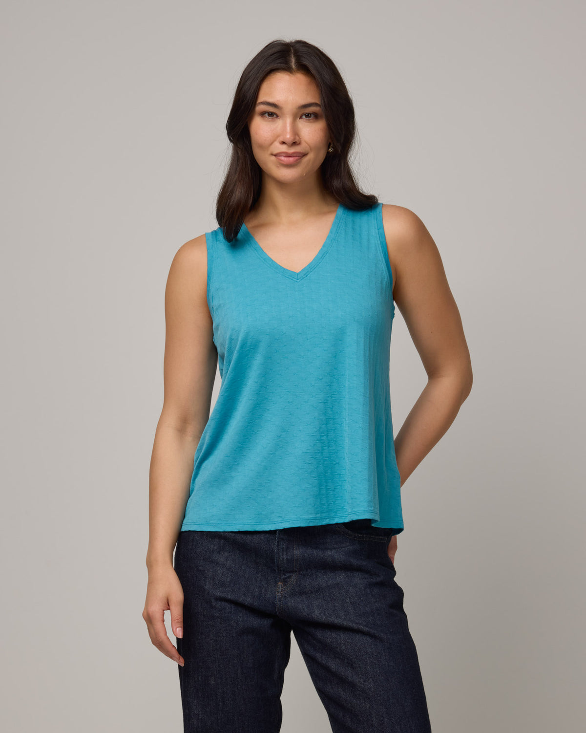 Model wearing Poppy Jacquard Reversible Tank in Sea Blue, a bright sky blue color. Poppy Signature Reversible Tank is a merino wool sleeveless, reversible, relaxed fit top available in sizes XS-3X.