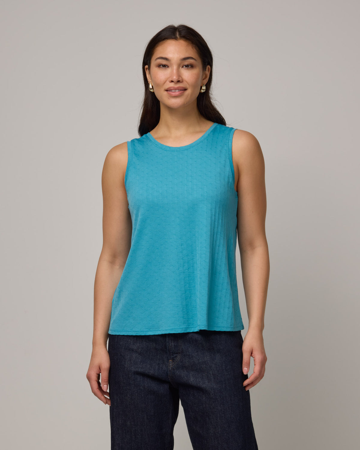 Model wearing Poppy Jacquard Reversible Tank in Sea Blue, a bright sky blue color. Poppy Signature Reversible Tank is a merino wool sleeveless, reversible, relaxed fit top available in sizes XS-3X.