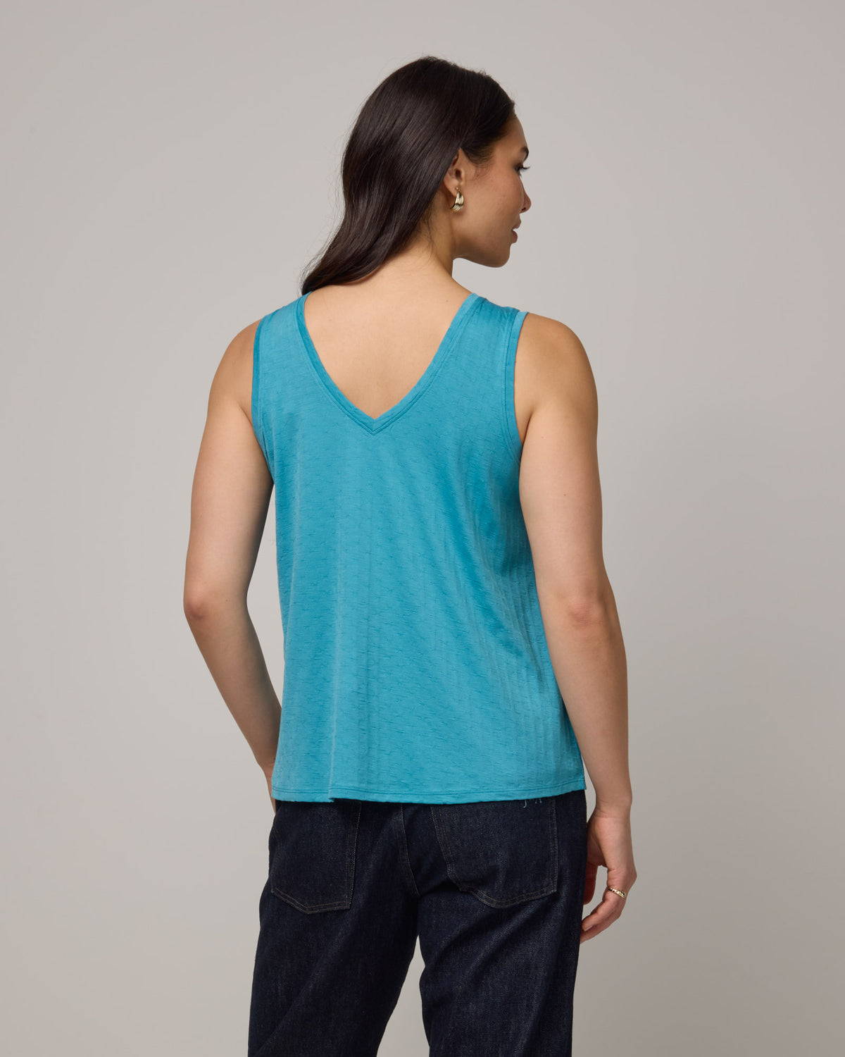 Model wearing Poppy Jacquard Reversible Tank in Sea Blue, a bright sky blue color. Poppy Signature Reversible Tank is a merino wool sleeveless, reversible, relaxed fit top available in sizes XS-3X.