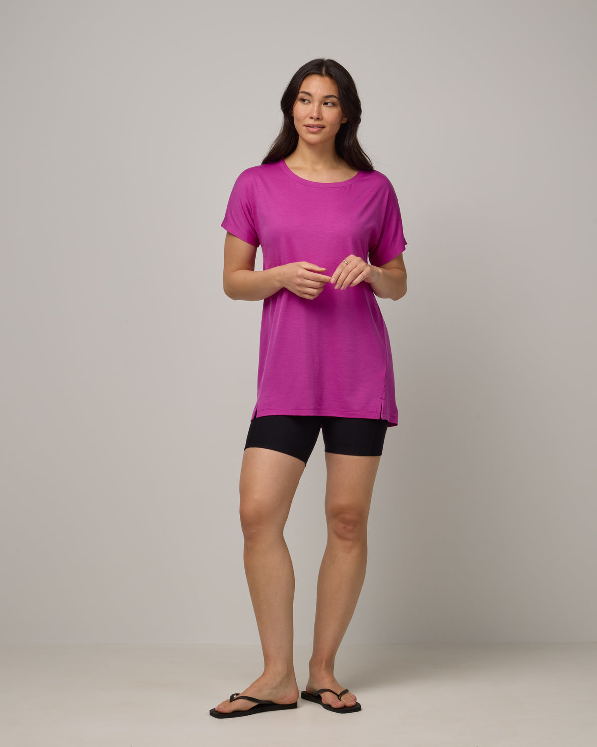Model wearing Jade Tunic Tee in Petunia, a bright fuchsia pink color. Jade Tunic Tee is a merino wool short sleeve, crew neck, relaxed fit tunic available in sizes XS-3X.
