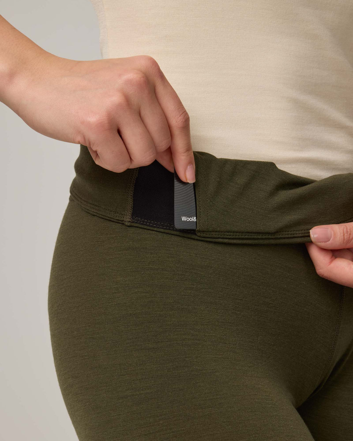 Waistband pocket detail of Roam Legging in Forest Night, a dark forest green color. Roam Legging is a lightweight merino wool legging with pockets available in sizes XS-3X.