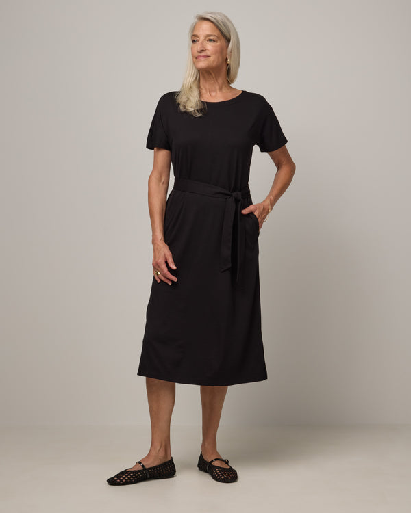 Model wearing Cora Shift Dress in Black. Cora Shift Dress is a merino wool short sleeve, midi shift dress with pockets and removable belt available in sizes XS-3X.