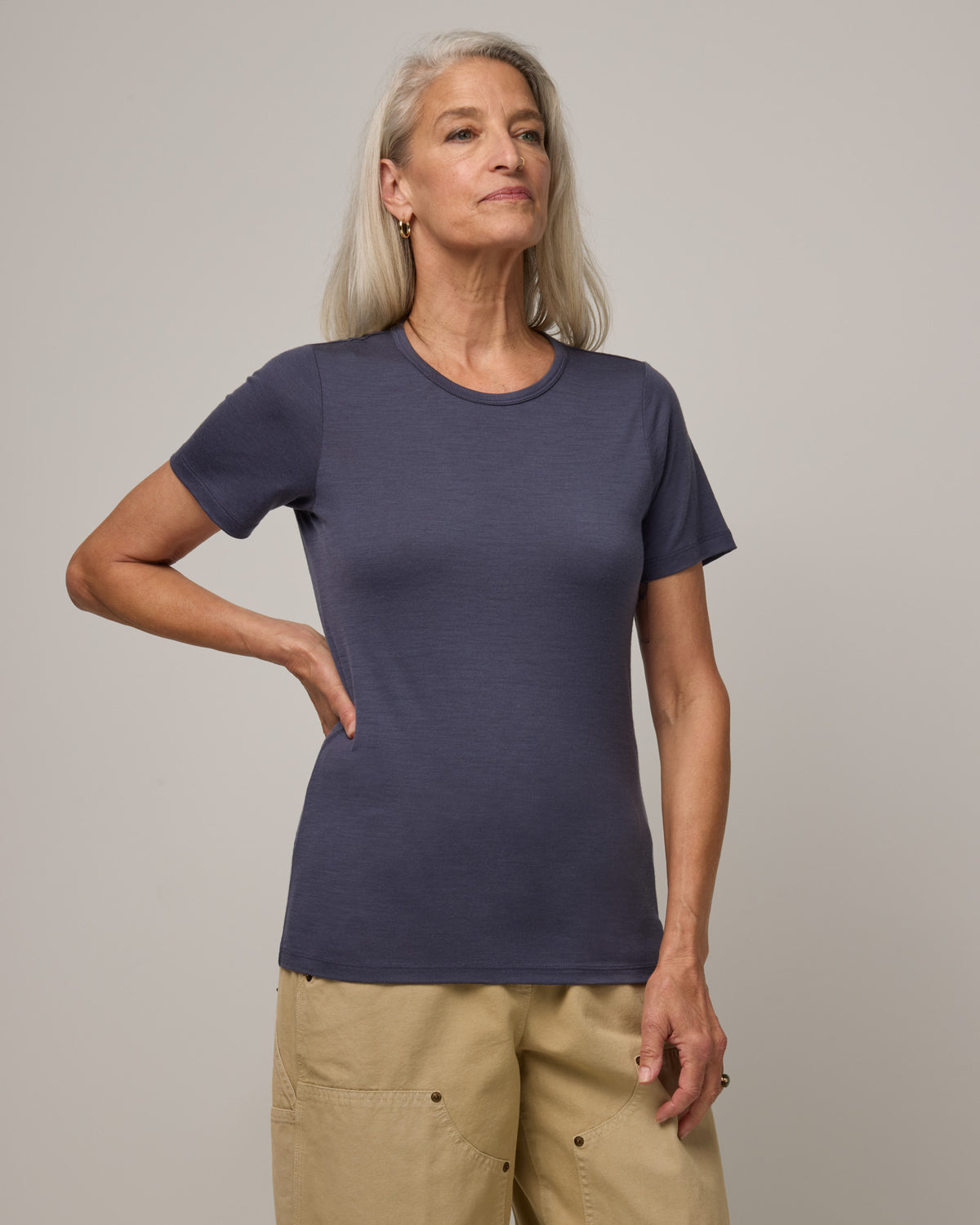 Model wearing Cara 100% Wool Fitted Tee in Odyssey Gray, a slate blue-gray color. Cara 100% Wool Fitted Tee is a merino wool short sleeve, crew neck, slim fit tee available in sizes XS-3X.