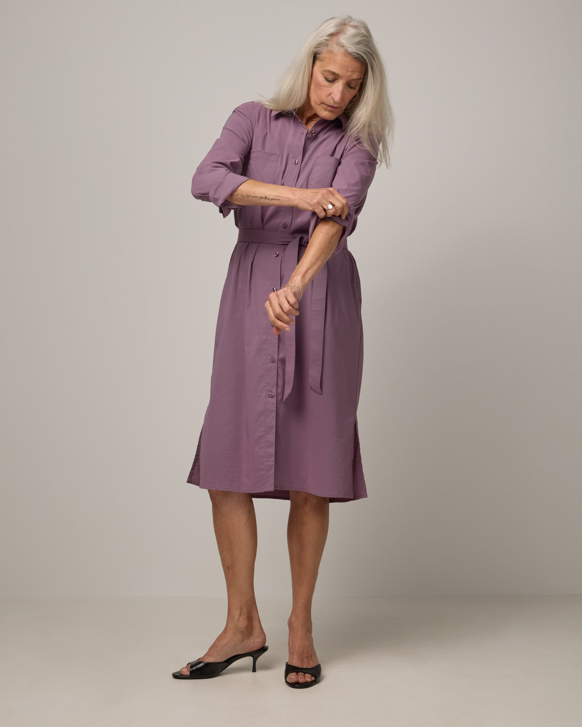Model wearing Victoria Shirt Dress in Lavender. Victoria Shirt Dress is a merino wool long sleeve, midi length, button-front dress with pockets and removable belt available in sizes XS-XXL.