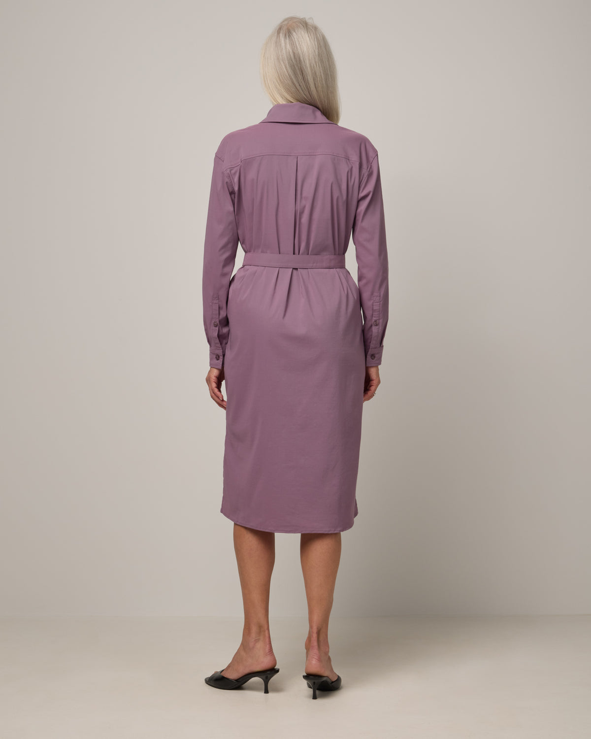 Model wearing Victoria Shirt Dress in Lavender. Victoria Shirt Dress is a merino wool long sleeve, midi length, button-front dress with pockets and removable belt available in sizes XS-XXL.